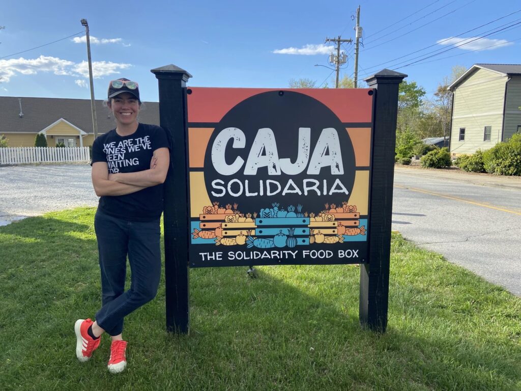 Cata Norena posing by the Caja Solidaria sign