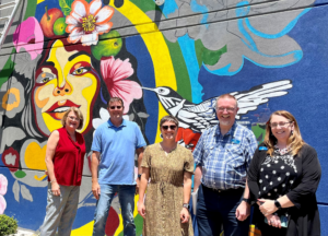 IAM and members of the Impact Health team in front of a mural